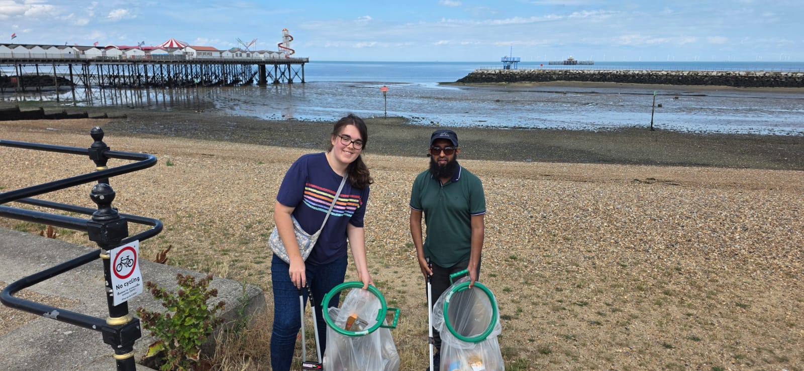 An image of two litter pickers with bags of rubbish from the beach